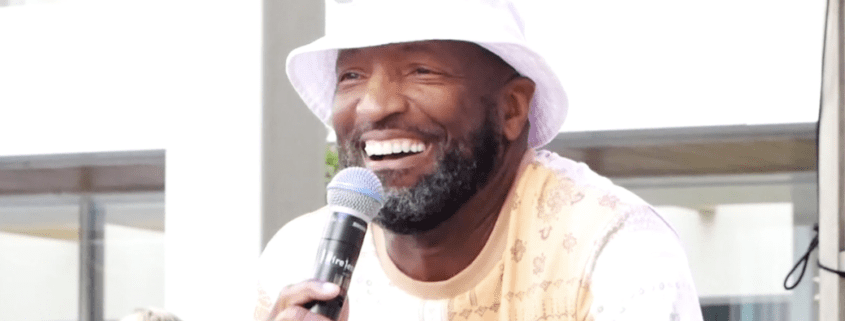 Man in white hat holding a microphone.